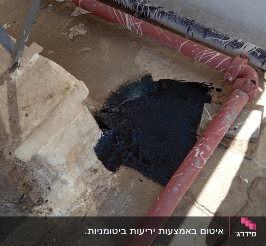 אזור אטום בזפת שחורה ליד צינור אדום